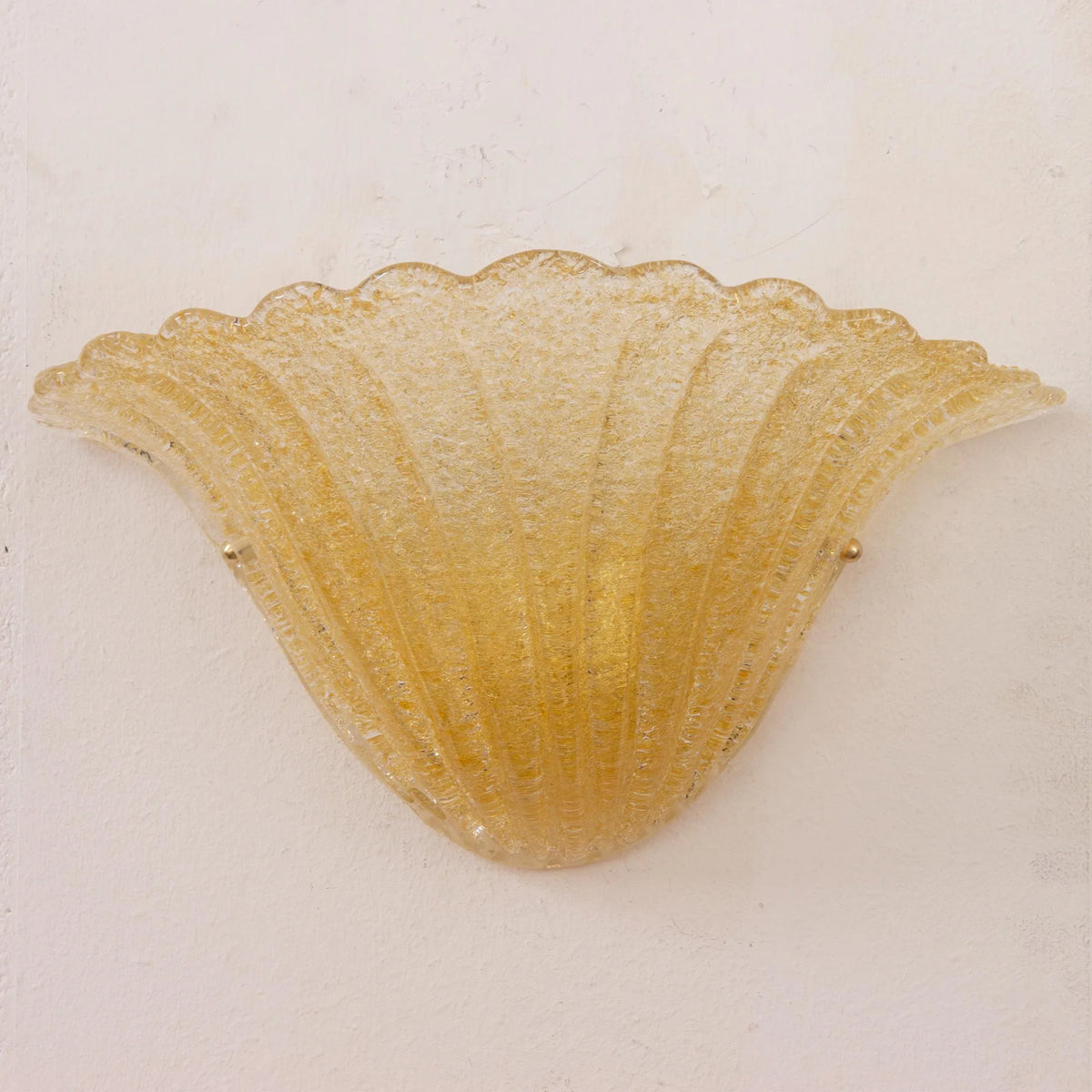 Amber Murano glass shell wall sconce, unlit, centered front view on a white wall