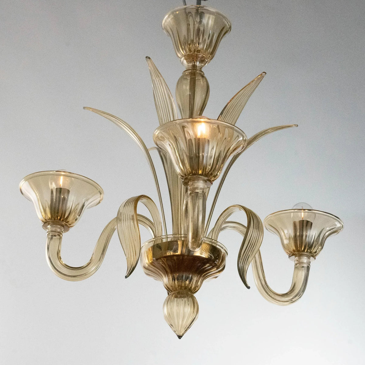 Amber Murano glass three-arm chandelier — illuminated angled view