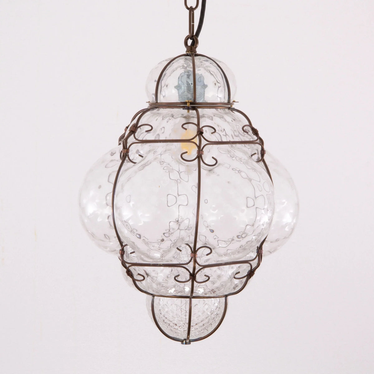 Clear Murano glass lantern pendant with scrollwork cage — illuminated with suspension chain