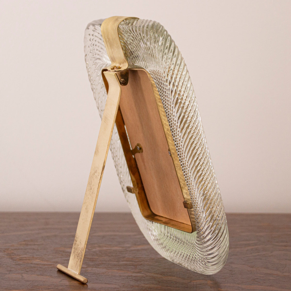 Side-back view of the clear Murano glass picture frame with brass easel stand