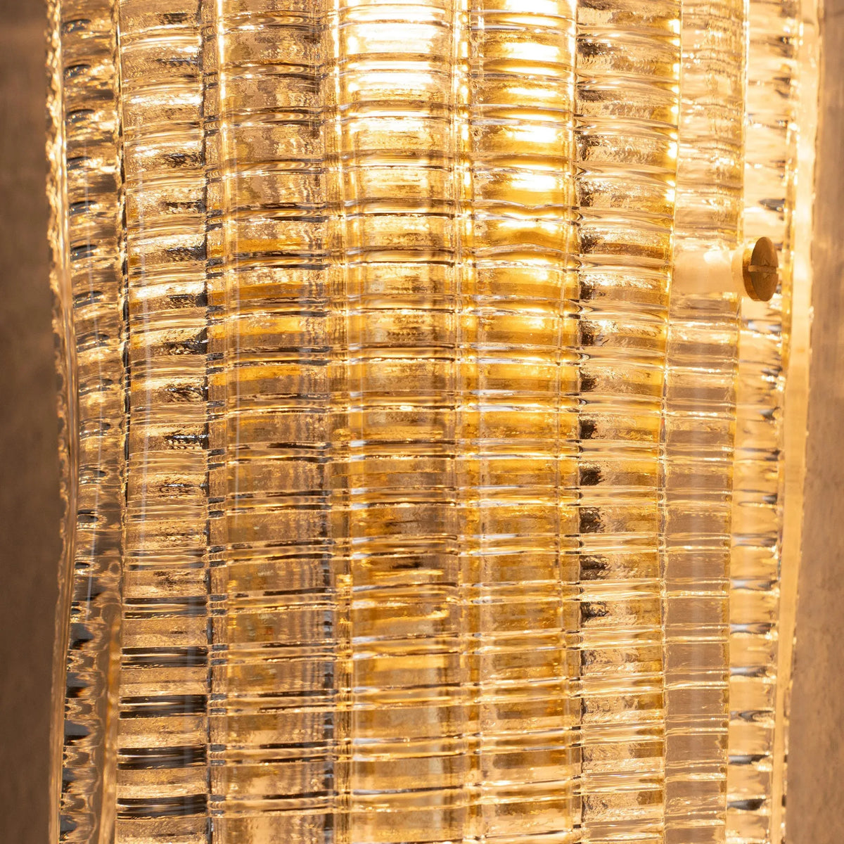 Macro of the ribbed texture of the lit clear Murano glass wall sconce