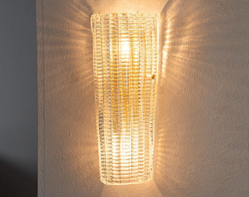 Clear textured Murano glass wall sconce, lit, casting light patterns on the wall