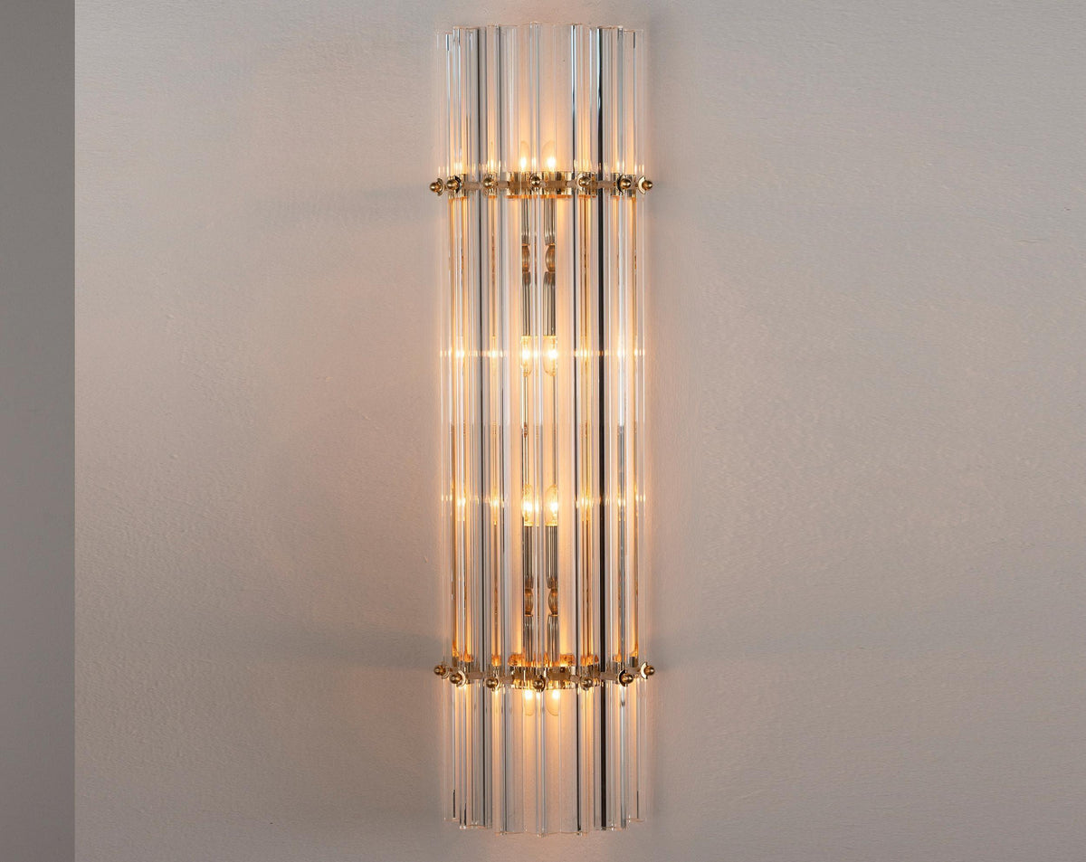 Tall clear Murano glass Triedri wall sconce with brass rings, lit, front view
