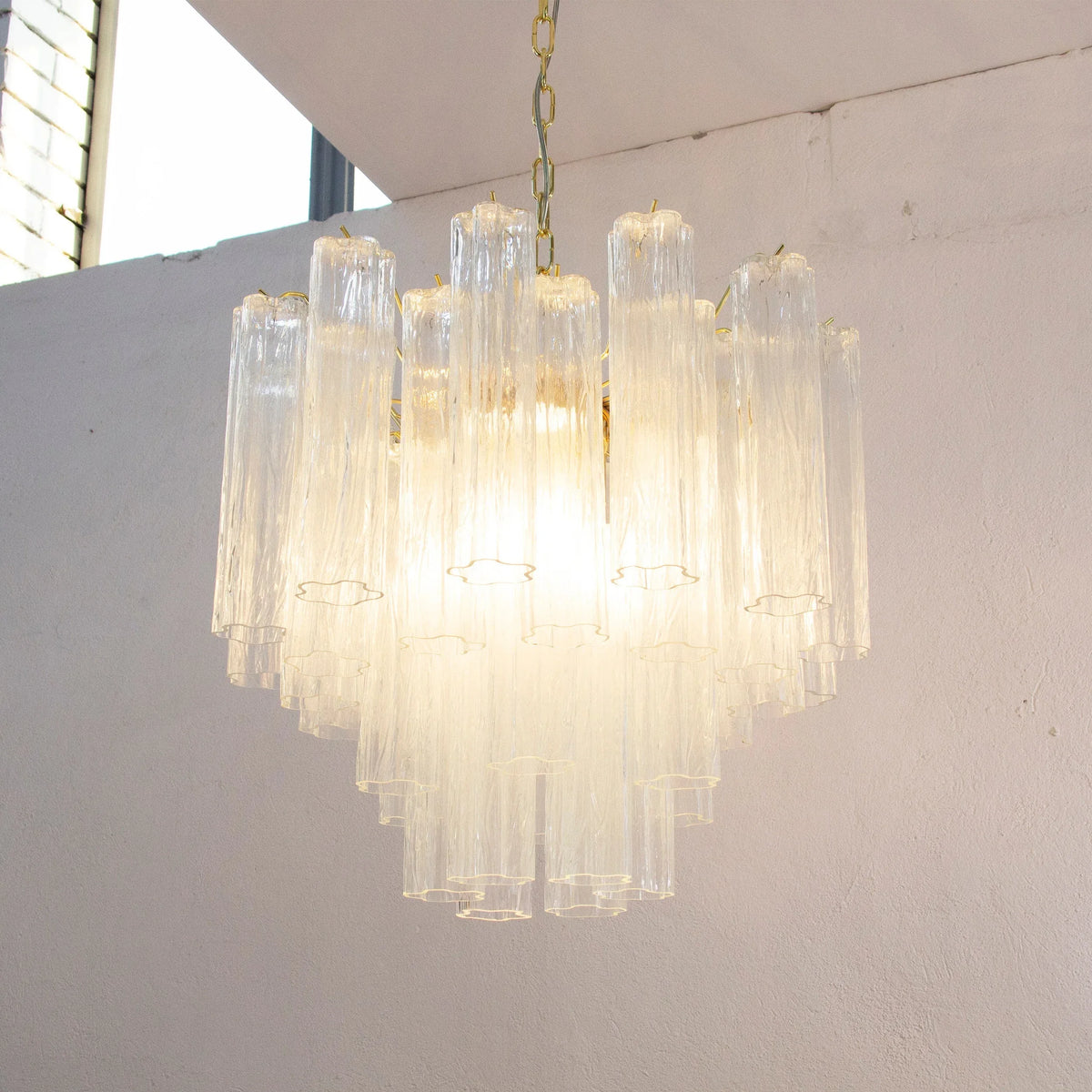 Clear Tronchi Murano glass chandelier — illuminated beside a window