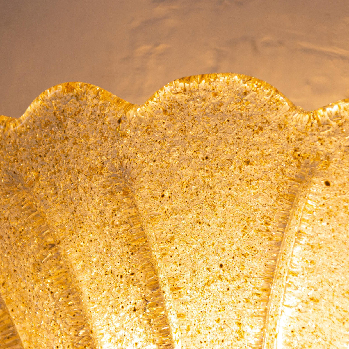 Macro of the lit gold Murano glass with graniglia inclusions and scalloped rim