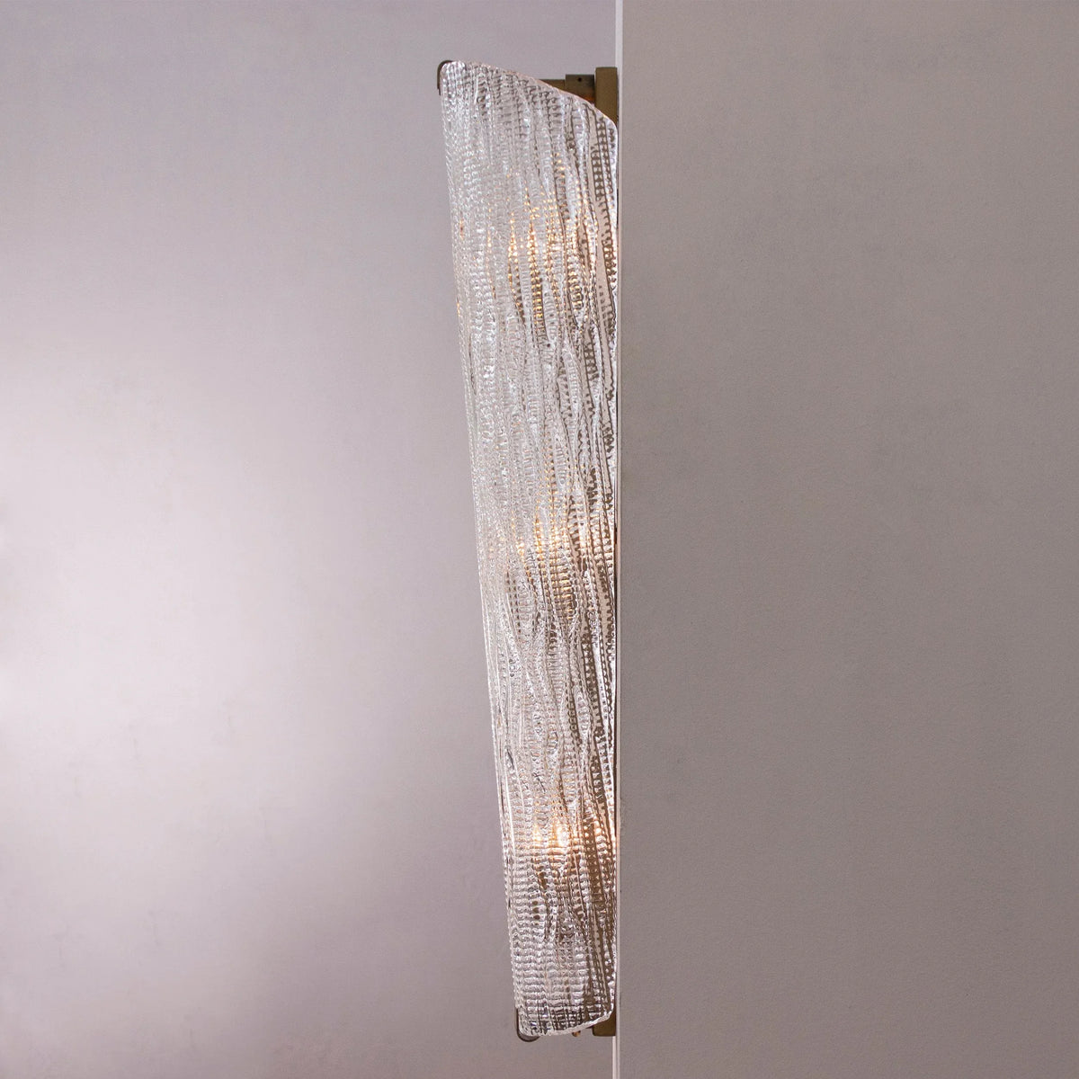 Side view of the tall textured Murano glass wall sconce showing its curved profile